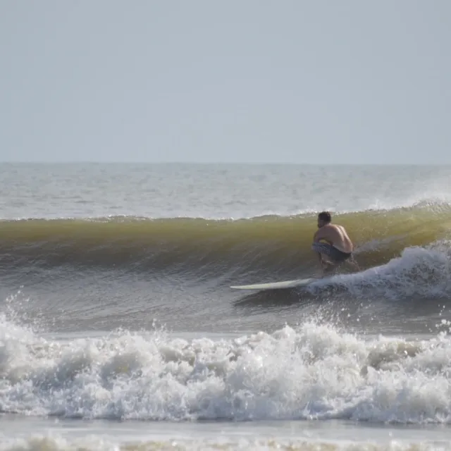 Surf student riding a green wave at Butler Beach during a lesson