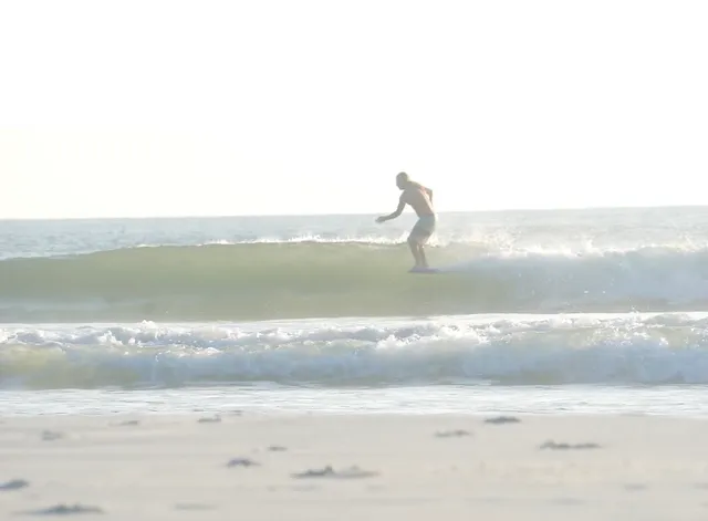 Surfer cross-stepping along the board while riding a wave near St. Augustine