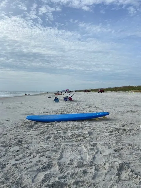 Blue soft-top surfboard resting on the sand at Butler Beach