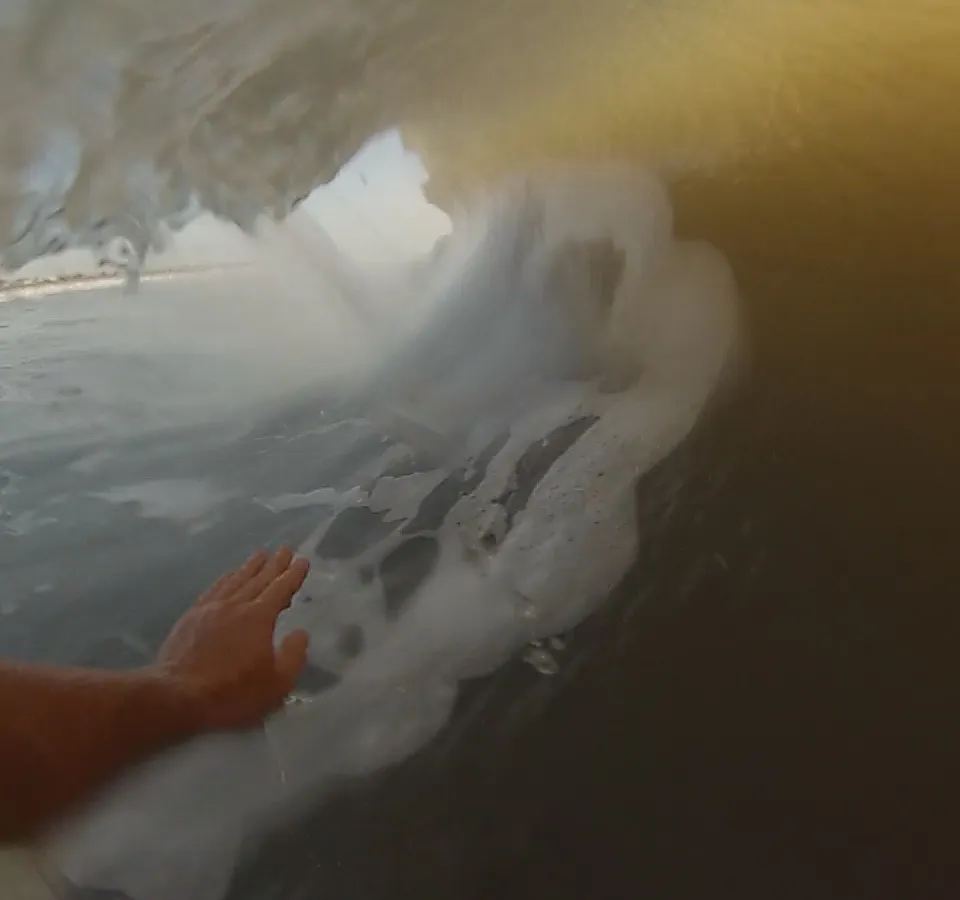 A hand skimming a curling wave at Butler Beach in St. Augustine, Florida